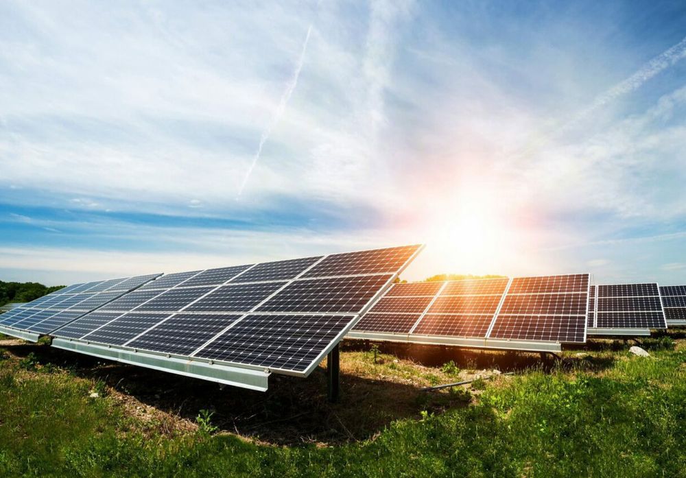Ground-mounted solar panels in a field under a bright sun